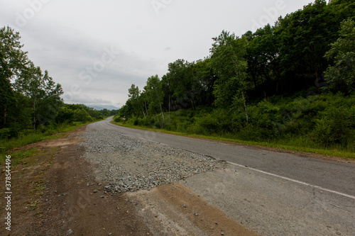 Very bad road in Russia. The asphalt road is all in holes in the middle of the forest.