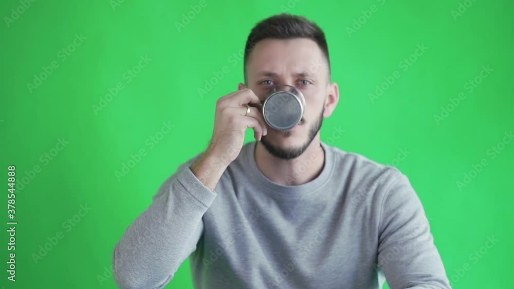Bearded man drinking hot tea from a metal cup on green screen Bearded man drinking hot tea from a metal cup on green screen