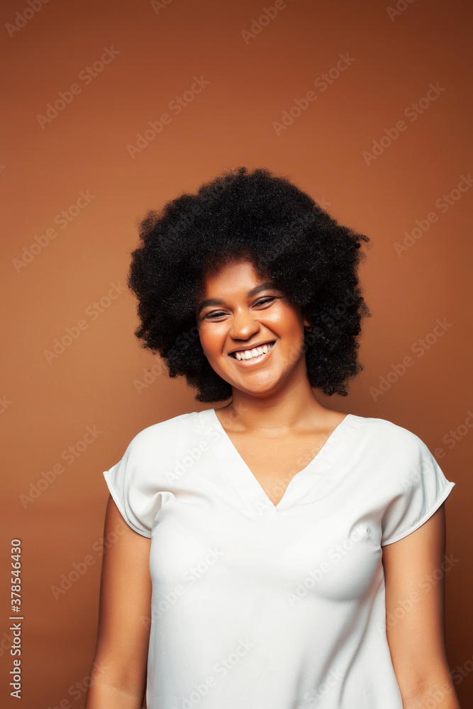 pretty young african american woman with curly hair posing cheerful gesturing on brown background, lifestyle people concept pretty young african american woman with curly hair posing cheerful gesturing on brown background, lifestyle people concept