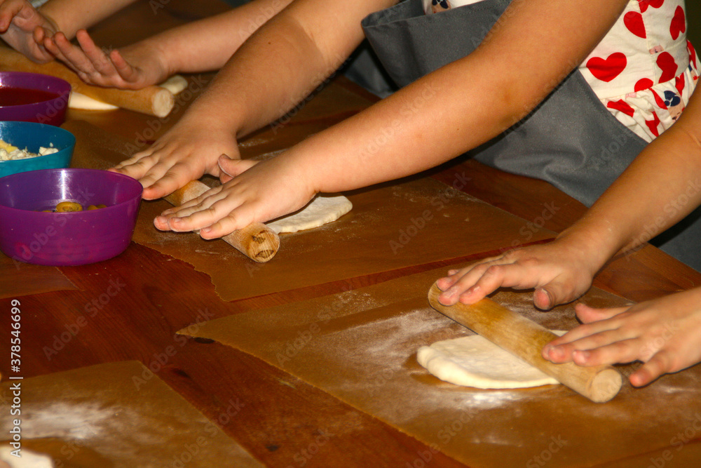 Children's hands close-up preparing dough products.