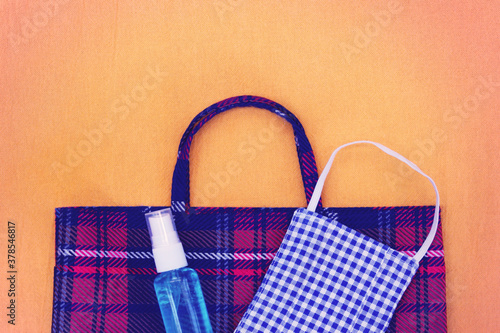 Fabric face mask ,hand sanitizer spray and cloth bag on orange background. Concept for the new normal or new lifestyle after COVID-19 Coronavirus pandemic. 