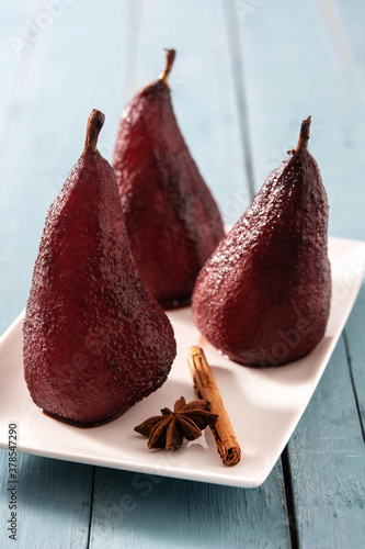 Poached pears in red wine on blue wooden table. 