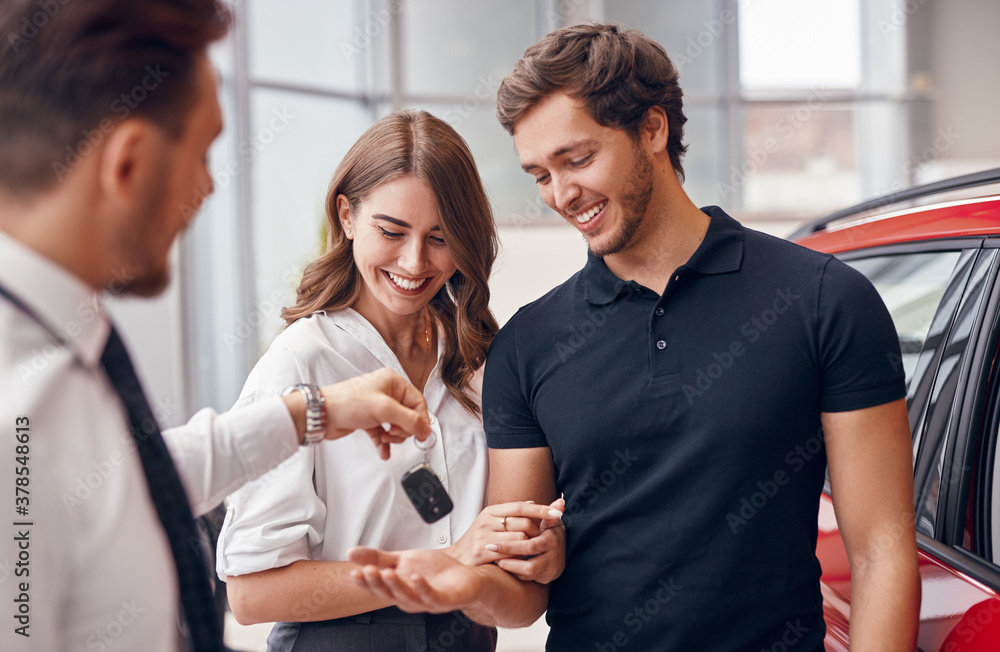 Salesman giving new car keys to happy couple Salesman giving new car keys to happy couple