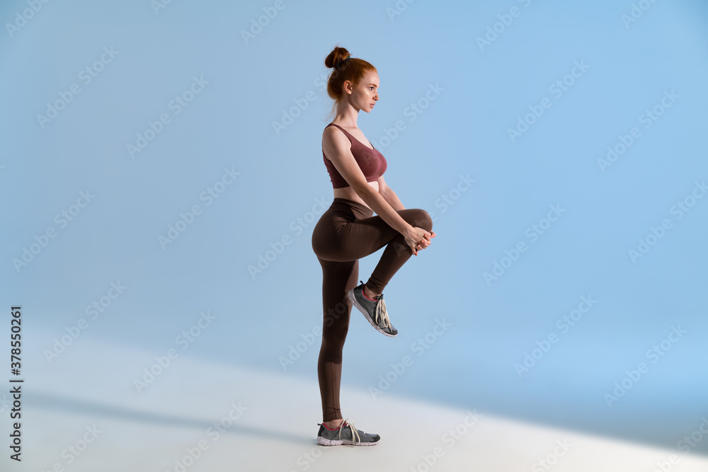 Photo of young focused sportswoman doing exercise while working out Photo of young focused sportswoman doing exercise while working out