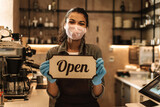 happy woman barista wearing medical mask showing open