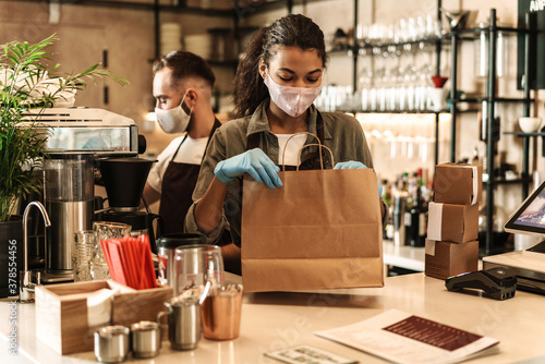 Two baristas wearing medical mask serving coffee