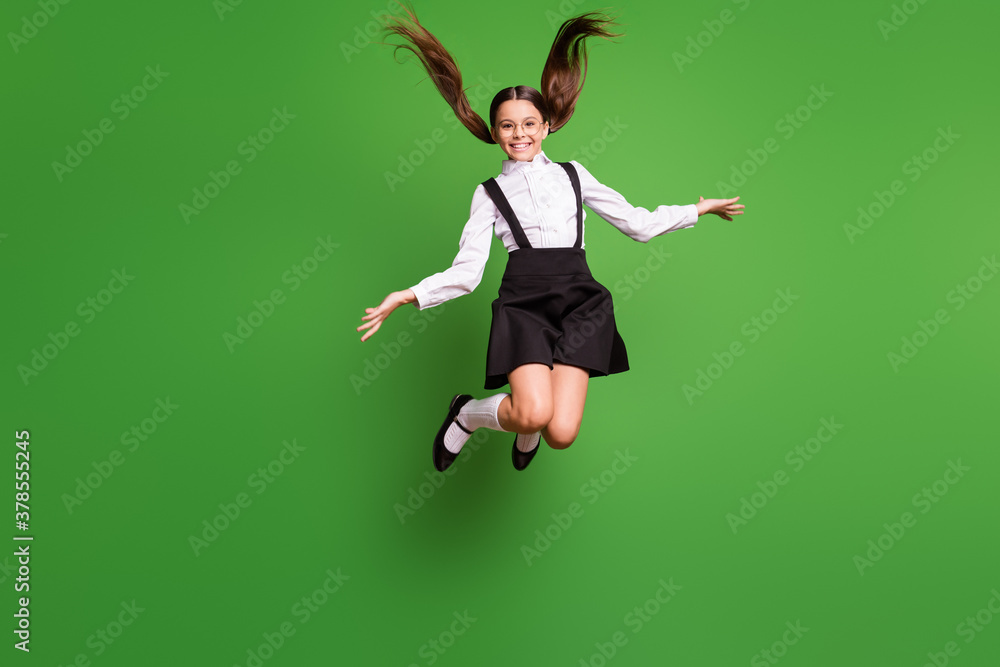 Photo portrait of girl jumping up high holding two blank spaces in hands wearing white socks isolated on vivid green colored background Photo portrait of girl jumping up high holding two blank spaces in hands wearing white socks isolated on vivid green colored background