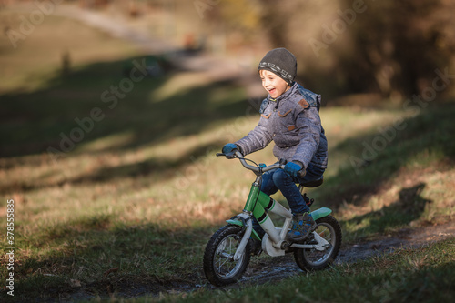 Six years old boy rides bicycle from the hill in the park.