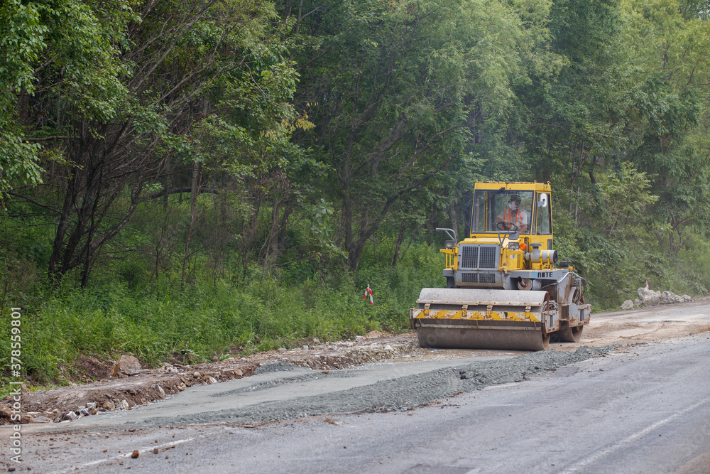 Summer, 2016 - Primorsky Krai, Russia - Repair of a bad road. Workers pave a bad road in a forest in Russia. Summer, 2016 - Primorsky Krai, Russia - Repair of a bad road. Workers pave a bad road in a forest in Russia.