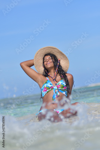 Hispanic woman with straw hat siting on shore beach laughing with close eyes and splash water. Happiness fantasy Concept © GARSPHOTO