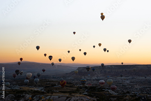 Colorful hot air balloons flying over Goreme National Park mountains at sunrise, Cappadocia, Turkey.