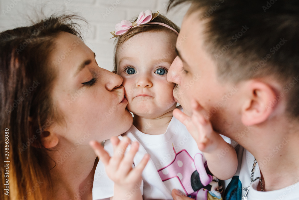 Happy family holidays. Mother, father, daughter on a white brick wall background. Sincere emotions concept. Happy family holidays. Mother, father, daughter on a white brick wall background. Sincere emotions concept.