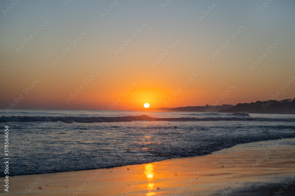 Falesia beach with the sun's reflection in the sand on the seashore at sunset. Olhos de Agua, Algarve, Portugal Falesia beach with the sun's reflection in the sand on the seashore at sunset. Olhos de Agua, Algarve, Portugal