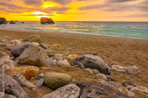 Sunset Over the Sea and Colorful Stones on a Sandy Beach