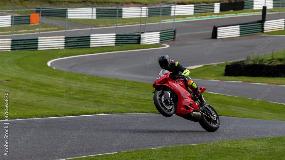 A shot of a racing bike on one wheel as it circuits a track.