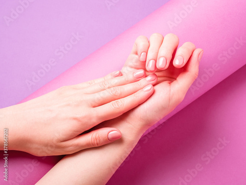 Beautiful female hands showing fresh cute manicure  skin and nail care concept  purple layout background