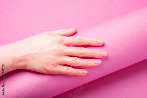 Beautiful female hand showing fresh cute manicure, skin and nail care concept, purple layout background