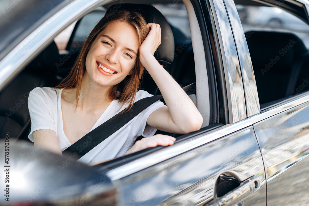 Attractive young girl smiling sincerely while driving a car.