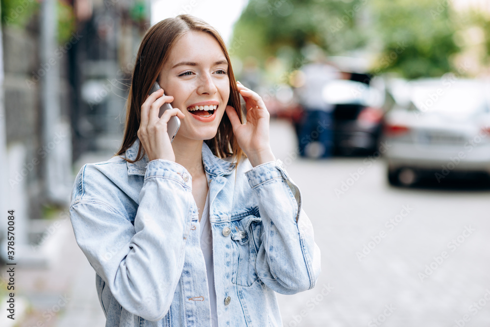 Smiling, cheerful girl outdoors talking on the phone Smiling, cheerful girl outdoors talking on the phone