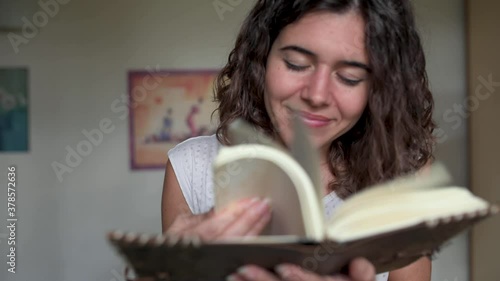 woman smiling while reading a book. Smelling the pages while leaf through a book. photo