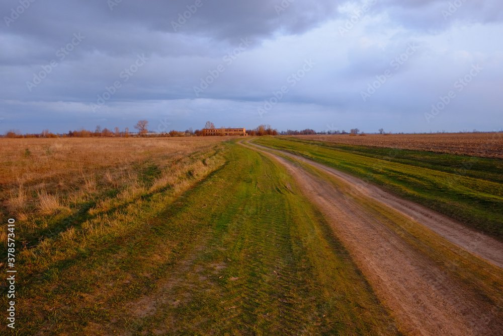 Country road among the fields in a late spring evening. Twilight landscape.