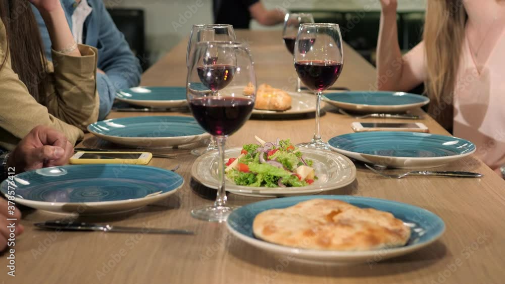Group of friends enjoying georgian meal in restaurant with glasses of wine Group of friends enjoying georgian meal in restaurant with glasses of wine