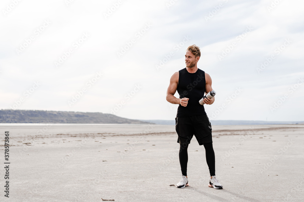 Photo of athletic young sportsman posing on summer beach Photo of athletic young sportsman posing on summer beach