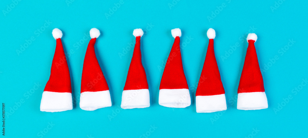 Top view of red Santa hats on colorful background. Merry Christmas Banner concept with copy space Top view of red Santa hats on colorful background. Merry Christmas Banner concept with copy space