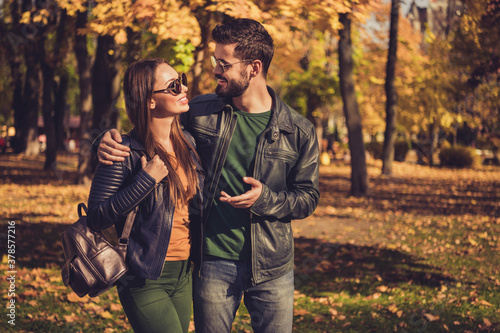 Photo of positive romantic couple talk walk in autumn september town park wear backpack casual jacket © deagreez