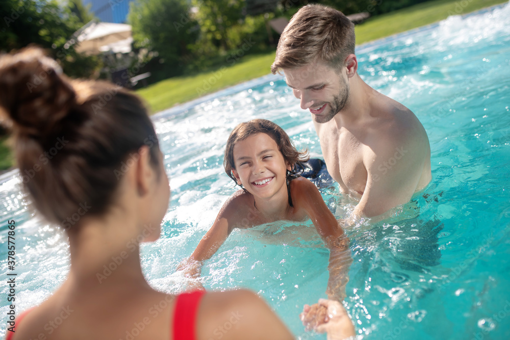 Happy parents teaching swimming to their son in the pool Happy parents teaching swimming to their son in the pool