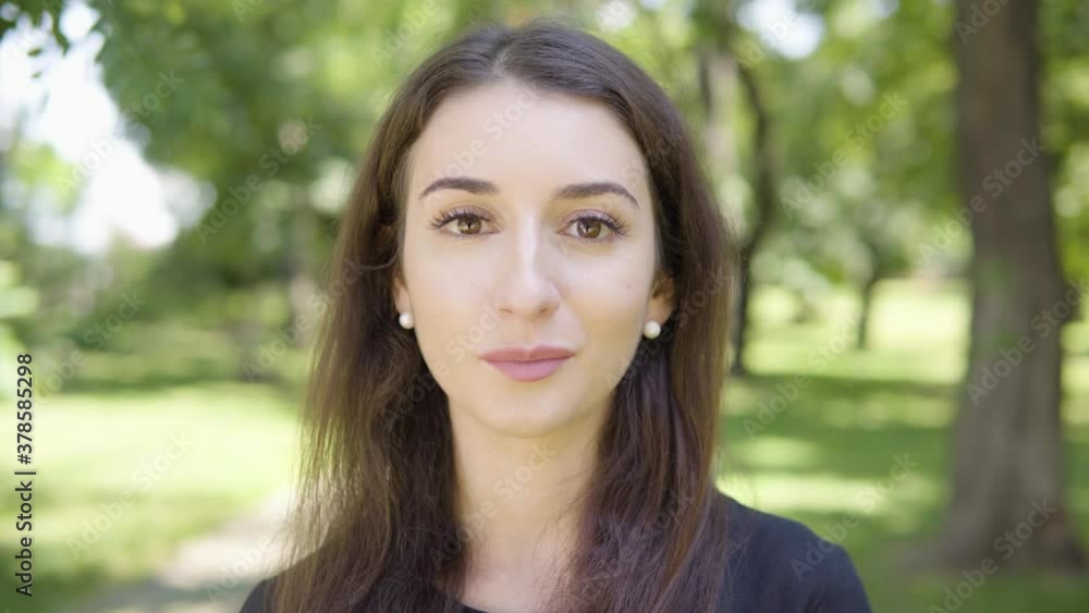A young Turkish woman talks to the camera in a park on a sunny day - face closeup A young Turkish woman talks to the camera in a park on a sunny day - face closeup
