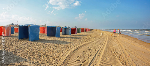 Early morning at Noordwijk beach: colorful wind breaks in a row along the surf waiting for customers