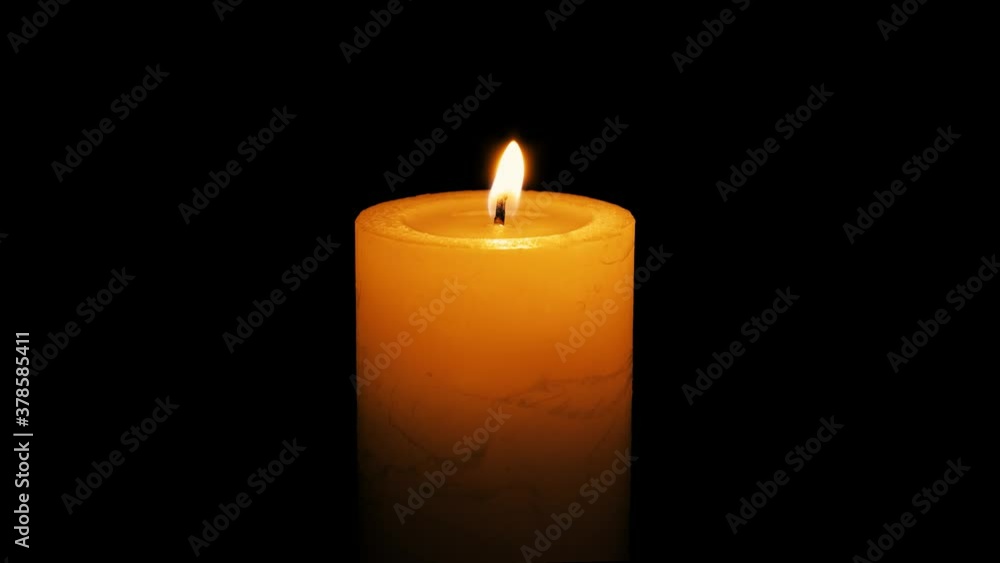A single white candle burning.Isolated candle burning with dark background.White paraffin candle with yellow shades burns on a black background.Background or illustration of remembrance or celebration A single white candle burning.Isolated candle burning with dark background.White paraffin candle with yellow shades burns on a black background.Background or illustration of remembrance or celebration