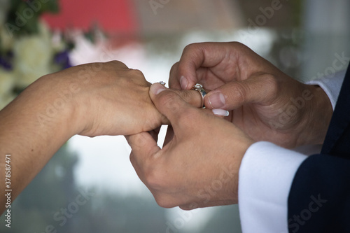 El novio poniendo el anillo a su esposa en su boda