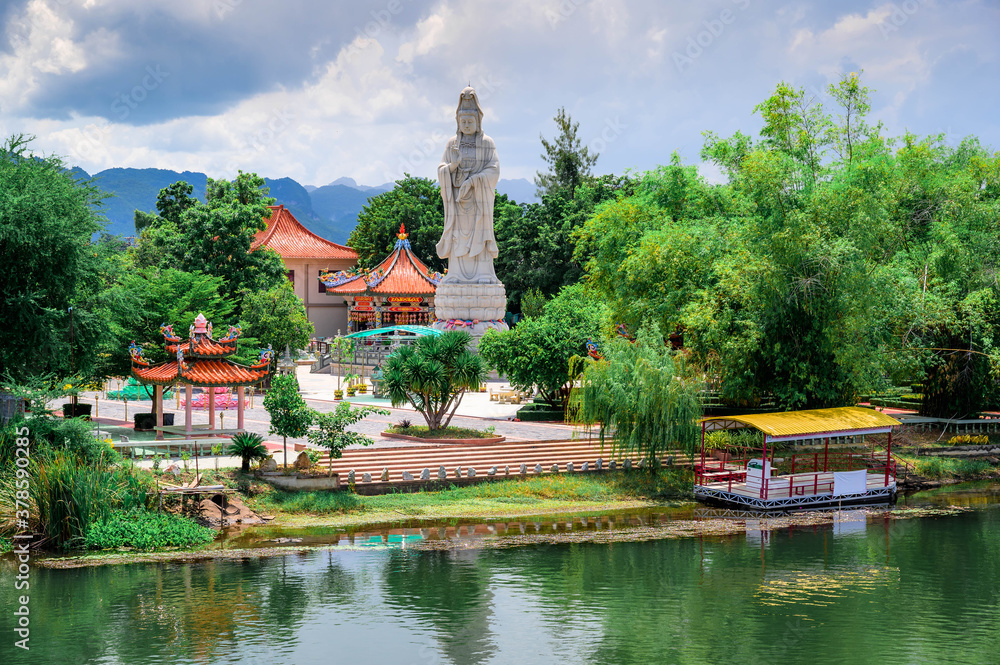 Landscape of Chinese-style Buddhist temple Kuang Im Chapel with statue of Guanyin (Chinese Goddess of Mercy) beside river Kwai, Kanchanaburi, Thailand. Wat Kuang Im Sunthorntham