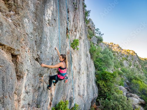 A woman in harness climbing a steep rock © malajscy