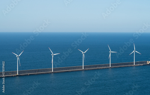 windmills on the sea next to sailboat