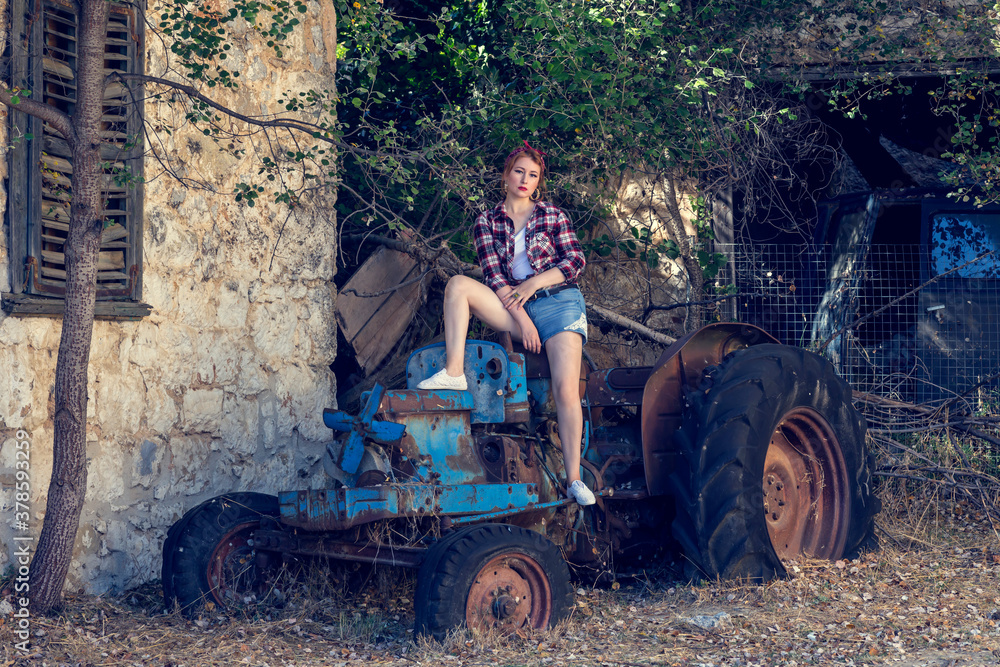 Fototapeta premium Young, beautiful girl sitting on a retro tractor close-up