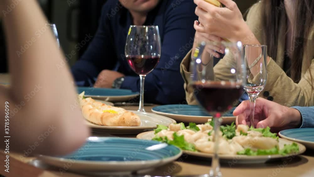 Group of friends enjoying georgian meal in restaurant with glasses of wine Group of friends enjoying georgian meal in restaurant with glasses of wine