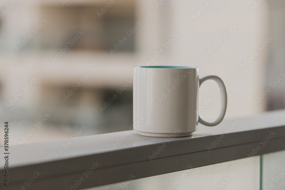 Close-up view of white blue coffee cup on sky terrace border on balcony with blurred morning city scape background. Selective focus and copy space. Beverage, breakfast. Hot tea in the mug. Morning. Close-up view of white blue coffee cup on sky terrace border on balcony with blurred morning city scape background. Selective focus and copy space. Beverage, breakfast. Hot tea in the mug. Morning.