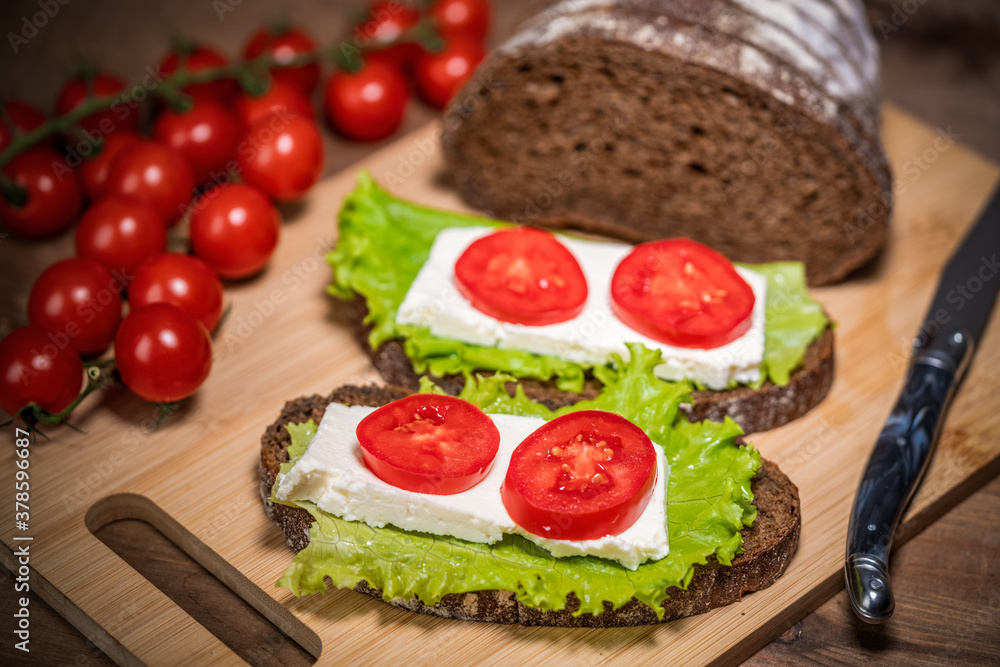 sandwich with cheese, lettuce and tomato on a wooden table sandwich with cheese, lettuce and tomato on a wooden table