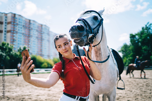 Jockey taking selfie with grey mare on smartphone