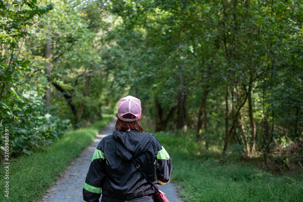 Obraz premium person walking in the woods along a path