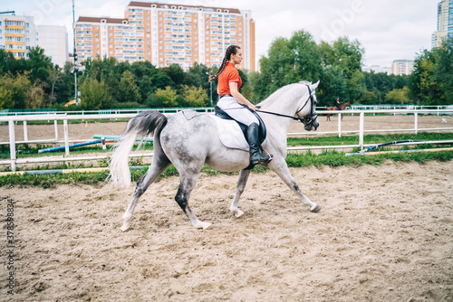 Female jockey riding gray stallion