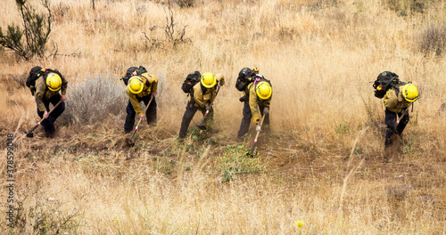 Foto Firemen firefighters in dry grass fighting the last of a fire preparing a firebreak