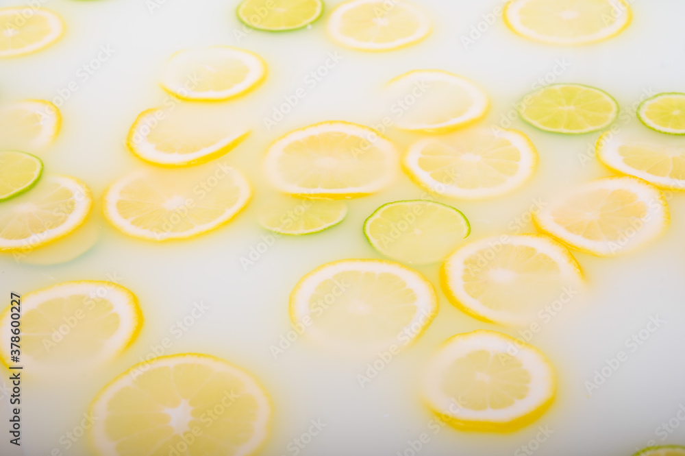 Turbid soapy water in the bath with slices of lemon and lime top view in full frame. Citrus. Spa with milk in the bath for rejuvenation.