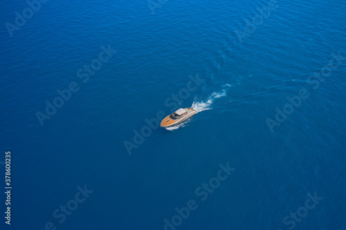 Aerial view luxury motor yacht. Yachts at the sea surface. High-speed yacht of white color on blue water in the rays of the sun top view. Travel - image.