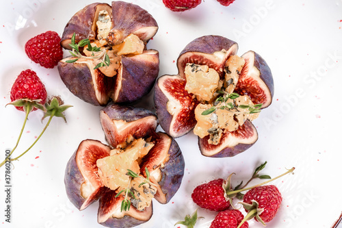 Fig floret appetizers with blue cheese, honey and raspberries, on a light background, top view