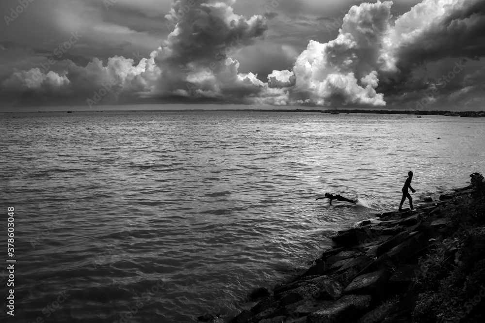 Fototapeta premium Children jumping in the river under cloudy sky. I captured this image from Chandpur , Bangladesh