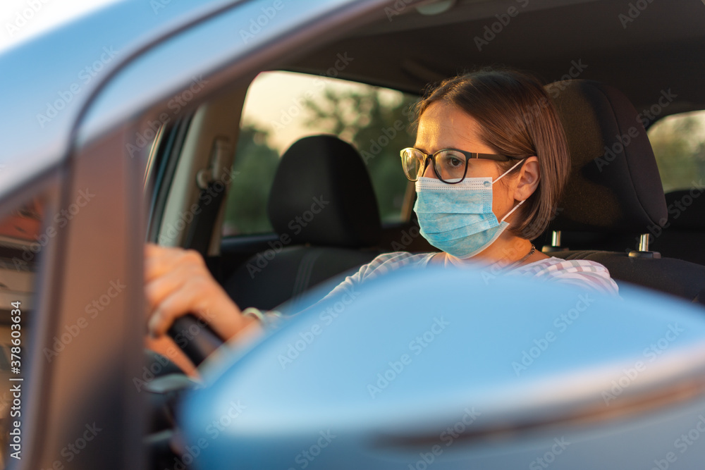 Beautiful female in a mask sitting in a car, protective mask against coronavirus. Beautiful female in a mask sitting in a car, protective mask against coronavirus.